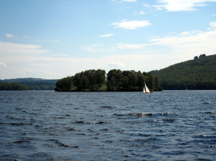 the water is very calm with a sailboat in it