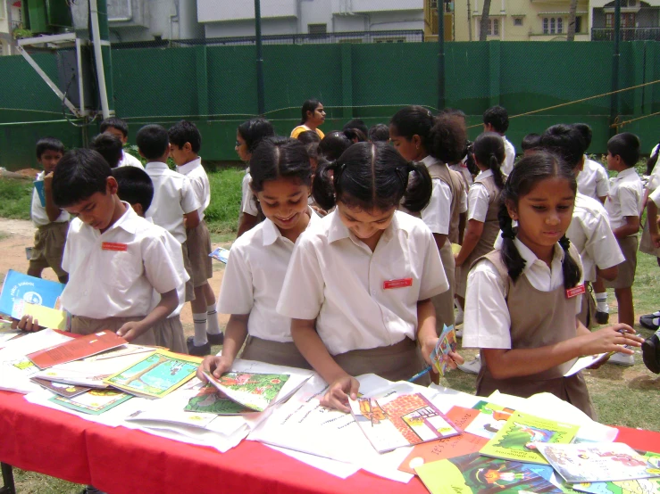 students stand around a long red table with open books on it