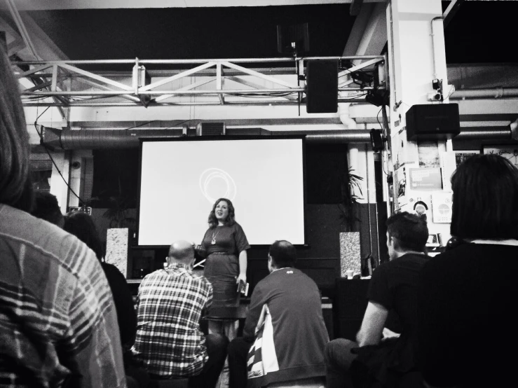 people watching a woman presenting on an interactive screen