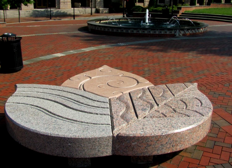 a stone bench sits in front of a fountain