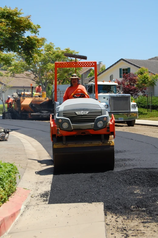 a man driving a road construction vehicle down a street