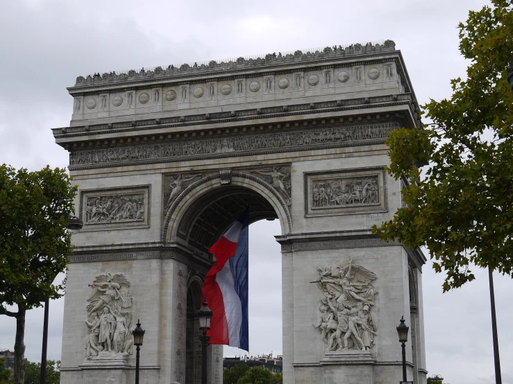 a flag is seen on the top of a large white triumph stone gate