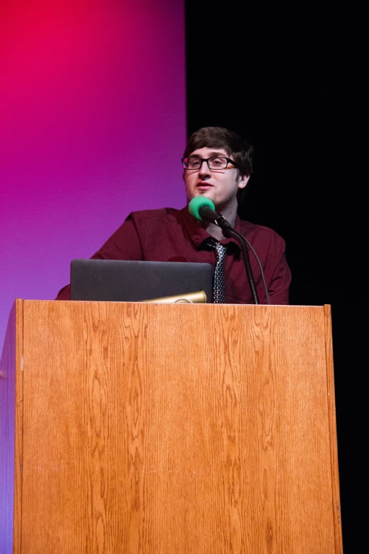 a man speaking from a podium next to a microphone