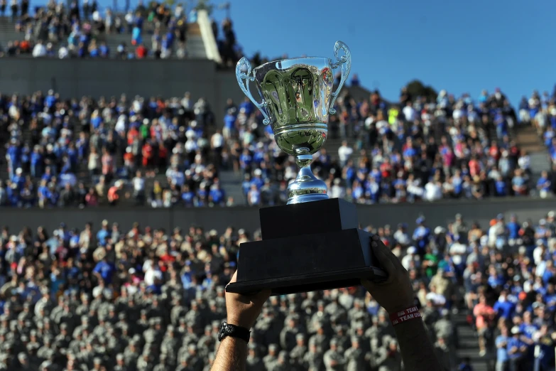 a person holds up a trophy with a stadium full of people