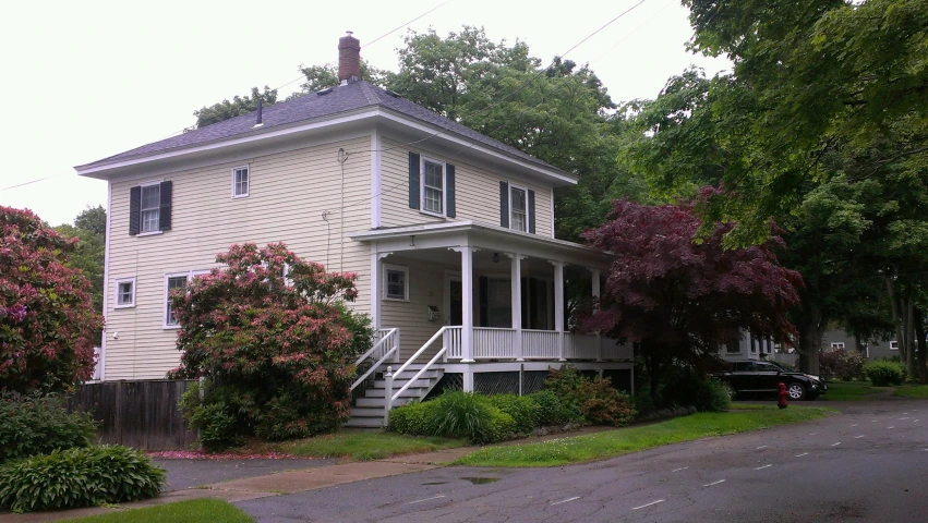 a white house with three stories is sitting on the corner of a street