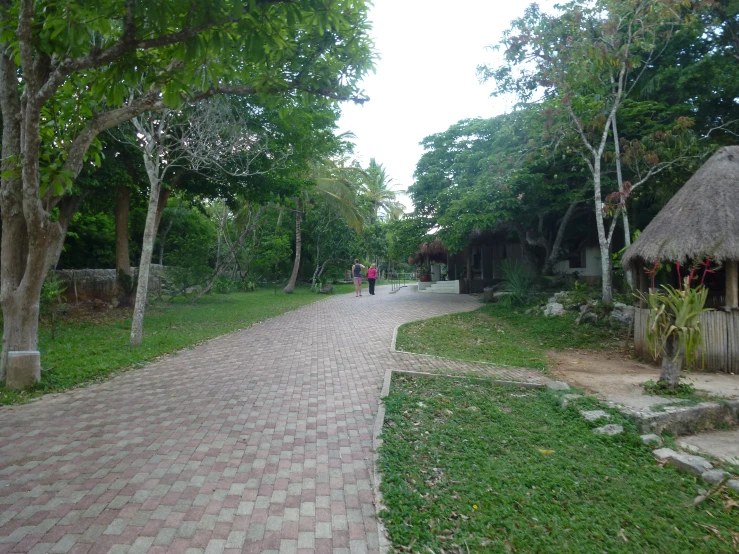 two people walk on a brick path in the park