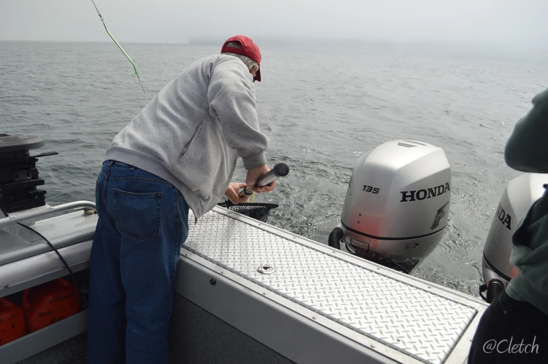 two people on a boat preparing to pull the outboard motor