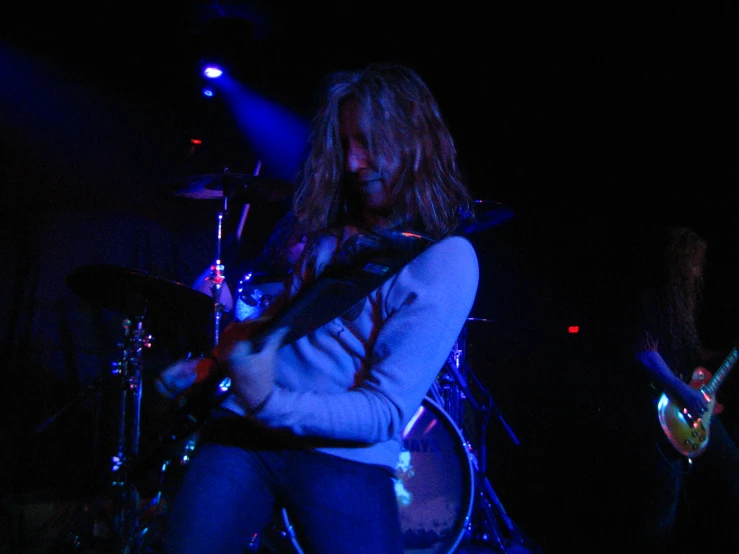 woman singing with guitar while she plays on the drums