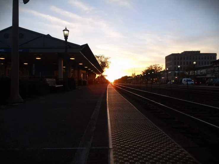 sunset on train tracks at the station in the evening