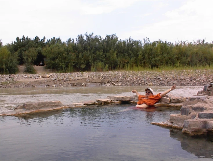 a person laying in water with rock ledges