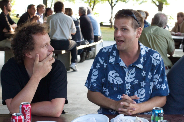 two men sitting at a table with drinks and sodas