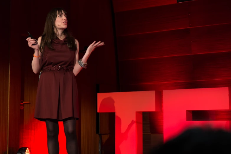 a woman with long hair and dress on stage talking