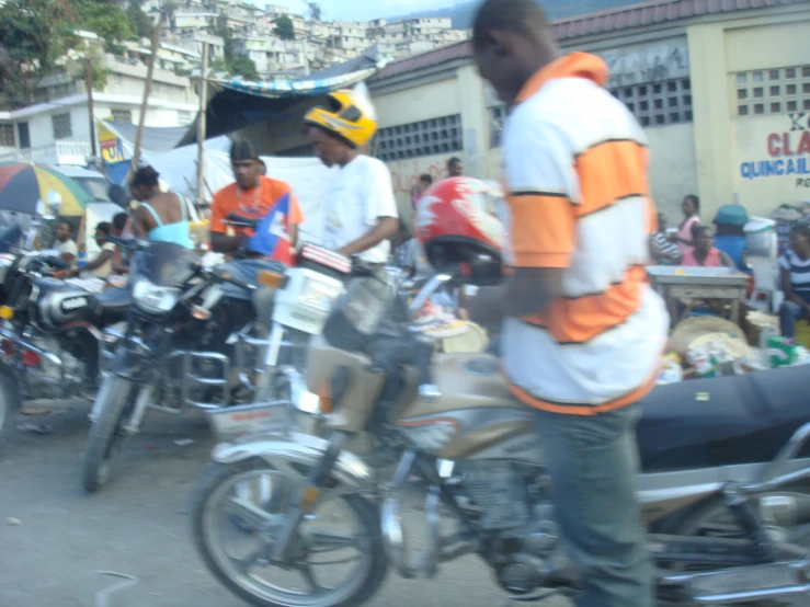 men are gathered at the side of a road on motorcycles