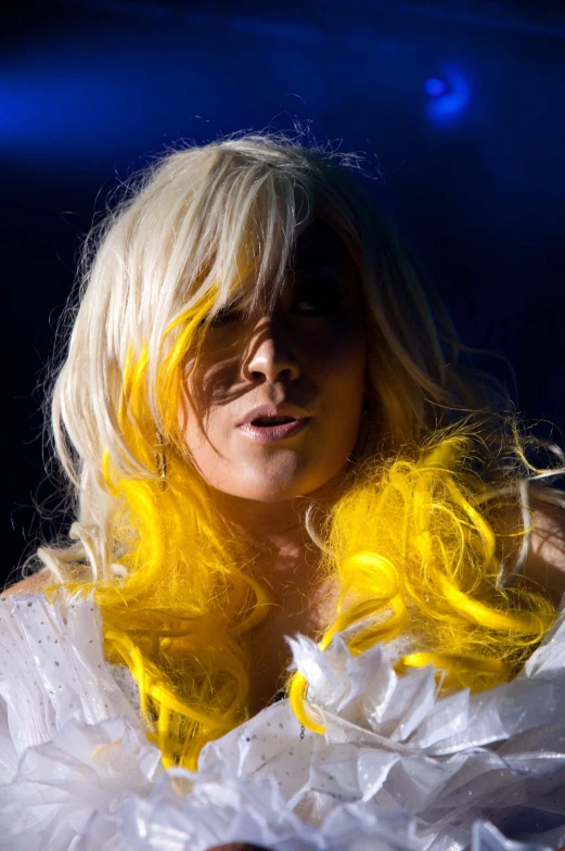 a woman in white dress with a yellow wig on stage