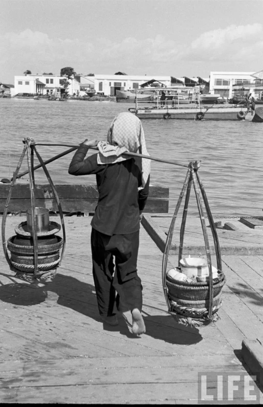 a man carrying two large objects over a body of water