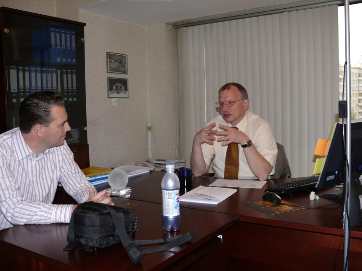 three men in a business meeting, one with his hand on his mouth