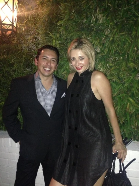 man and woman posing for a picture in front of an herb wall