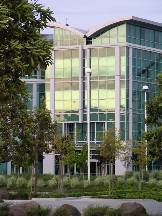 an office building has a glass front that reflects off the trees