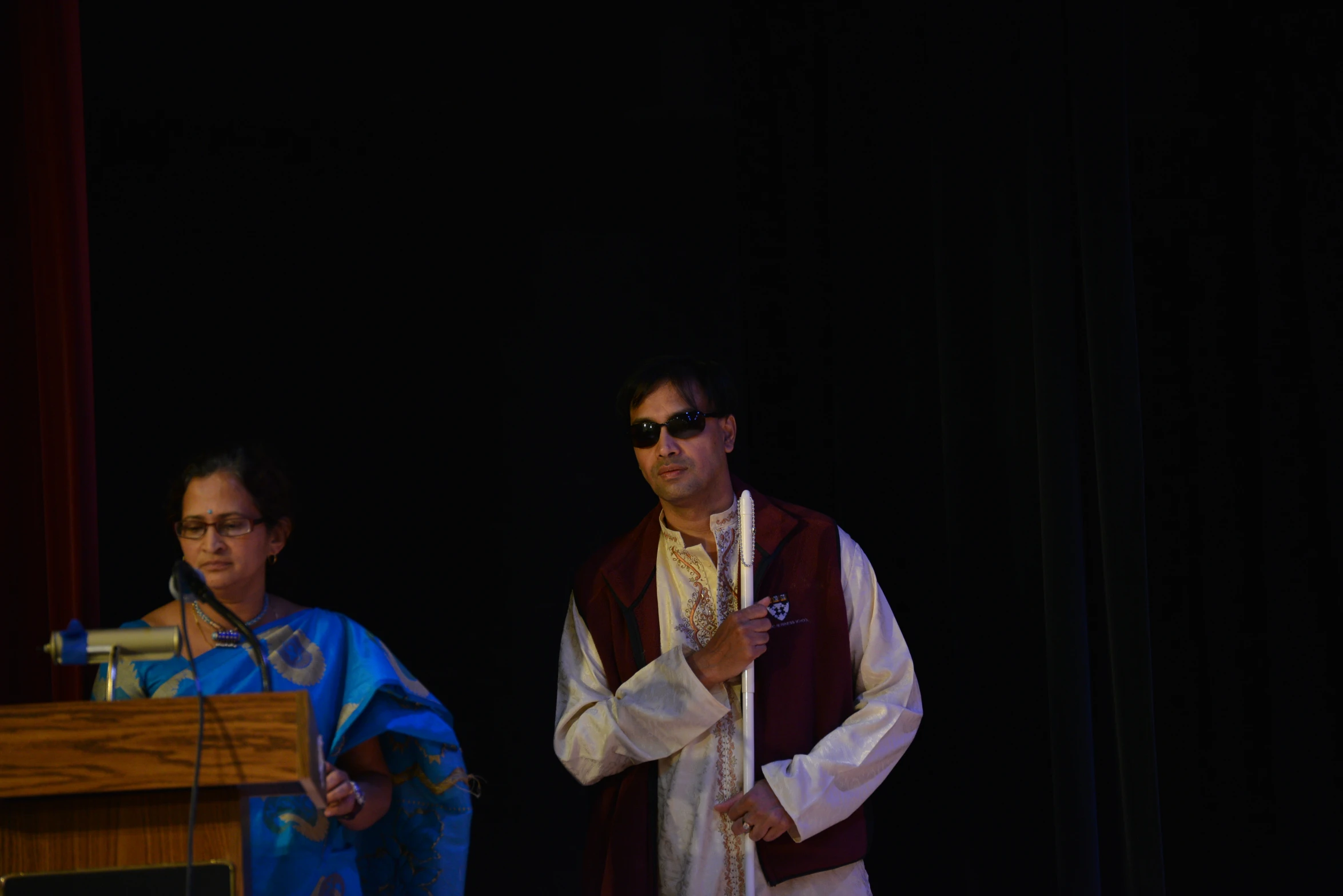 a man in a priest outfit and two people standing on stage