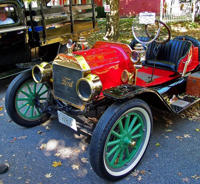 an antique car with a painted body, with a horse - drawn carriage in the back