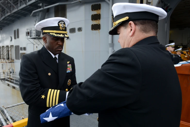 two men shaking hands on the deck of a ship