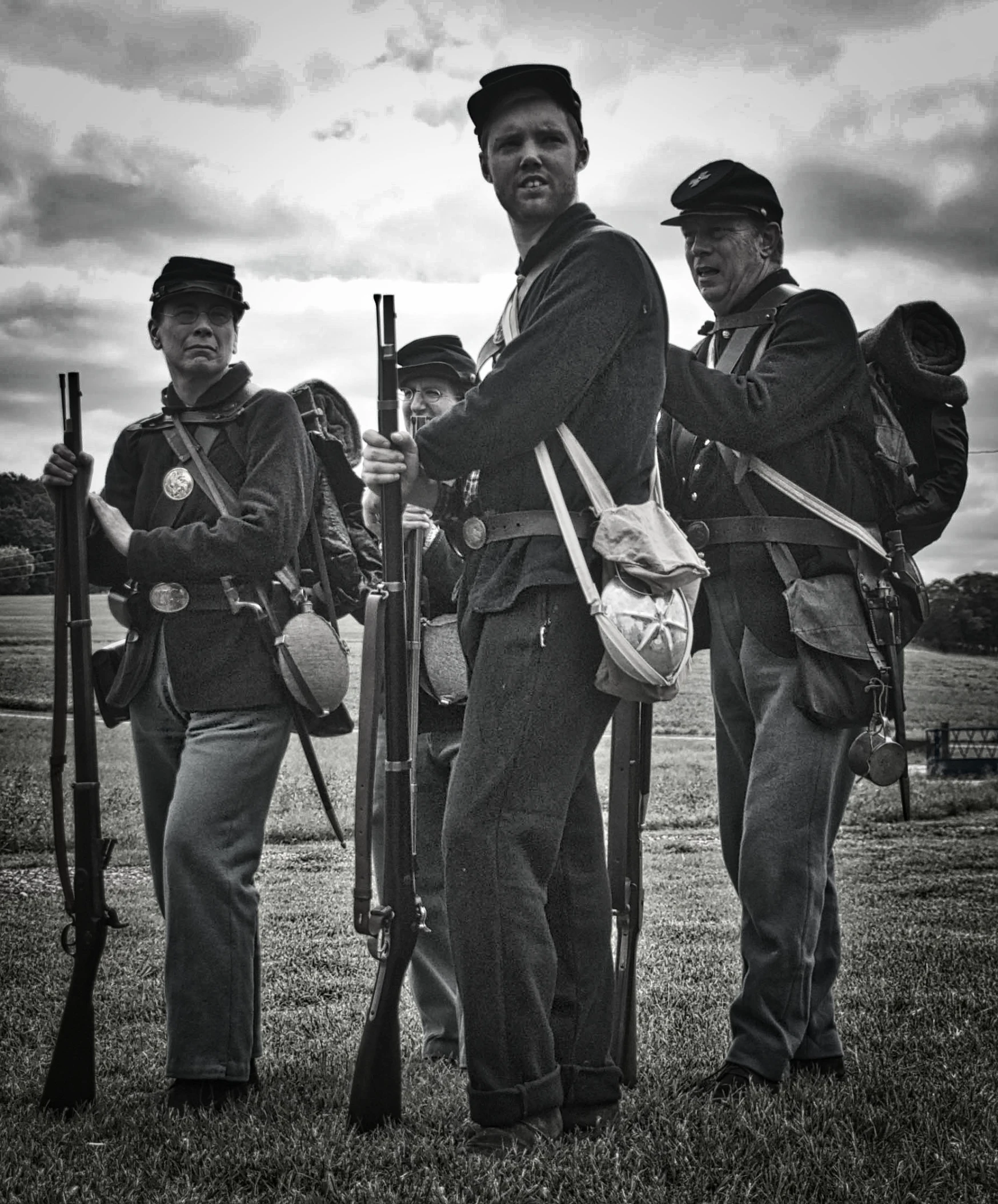 men in uniforms with guns stand together on the grass