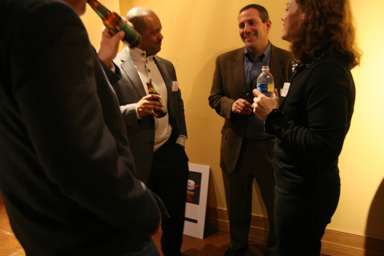 three men laughing and talking as one man takes a drink from a glass