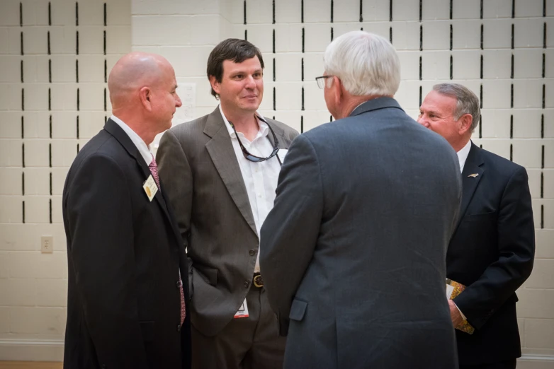 a group of men are talking with one man in business attire