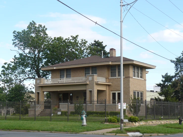 a brown house with green grass and trees in front