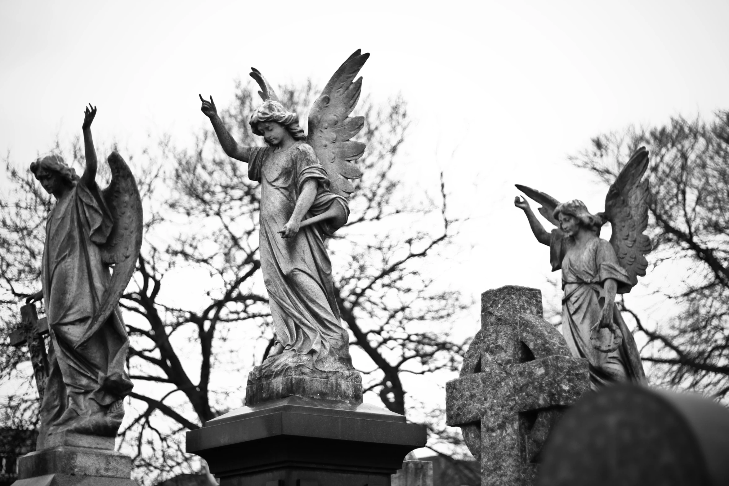 the three angel statues stand in a graveyard