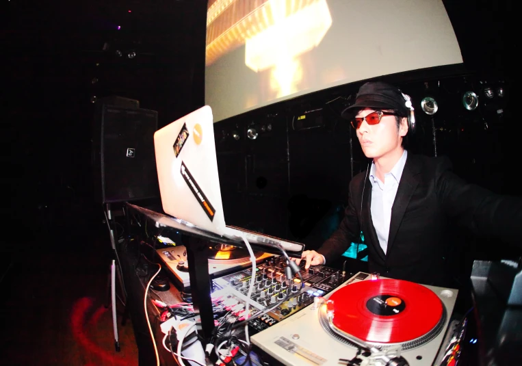 dj with equipment performing at nightclub at large screen