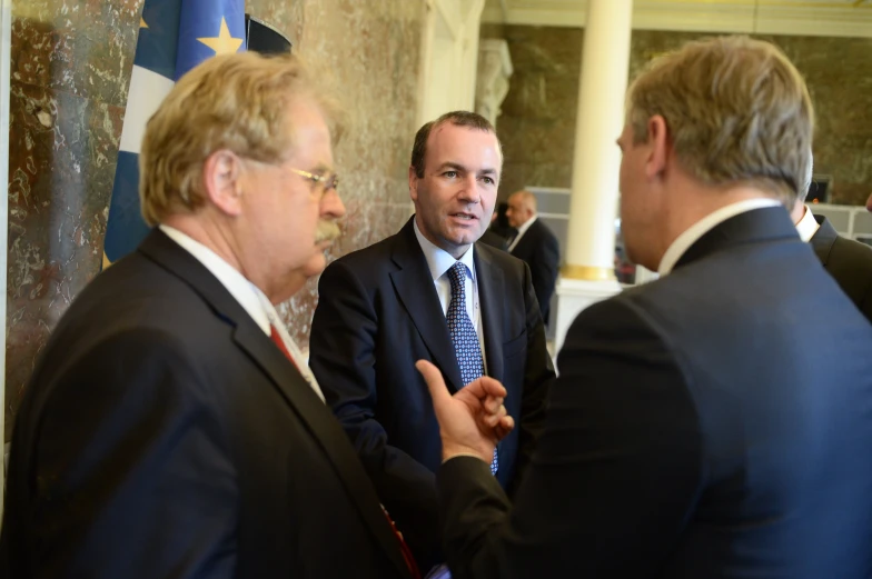 three men in suits talking to each other