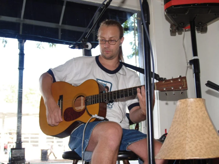 a man sitting in front of a microphone holding a guitar