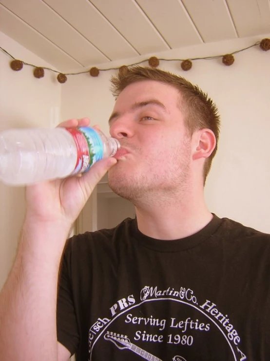 a young man who has drinks from a plastic bottle