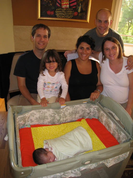 a group of people posing with a baby in a bed