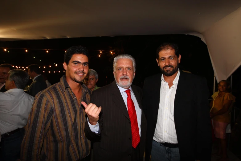 three men pose for the camera wearing suits