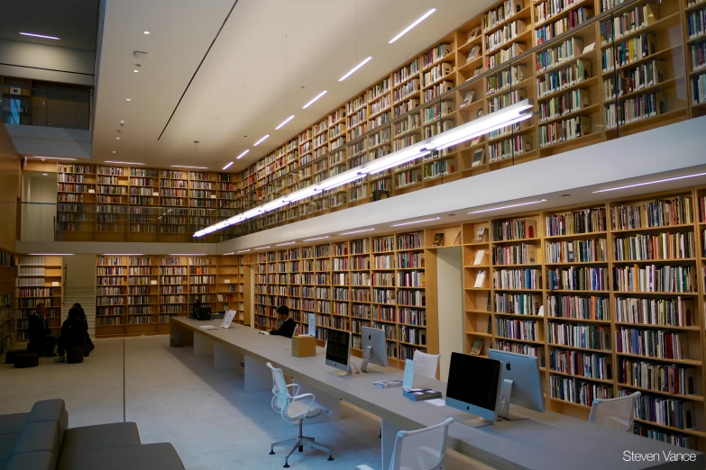 large group of computer desks sit in front of a wall of books