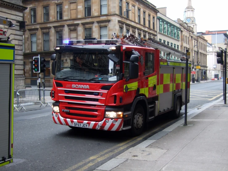 a fire truck that is parked next to the sidewalk