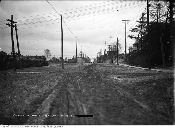 an old picture of a dirt road with telephone poles on each side