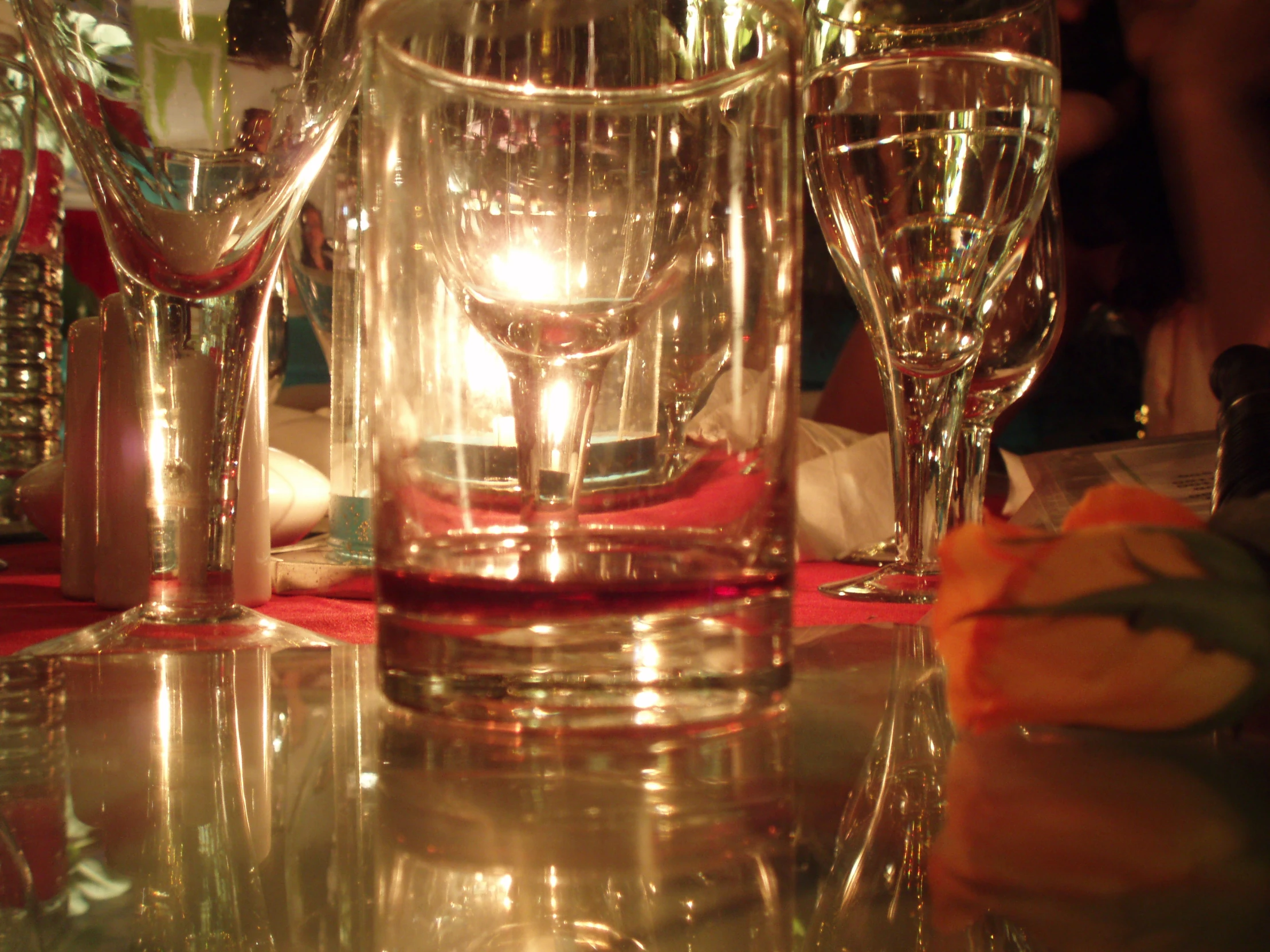 the table has several glasses on it, one with a candle inside