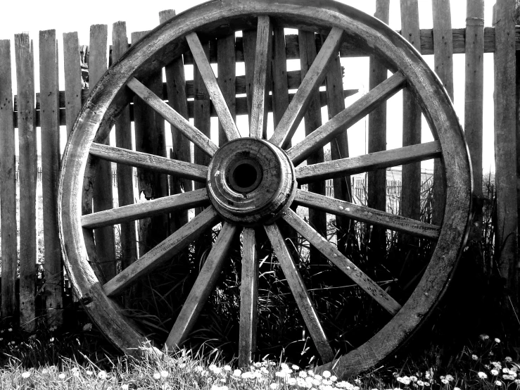 a wooden wagon wheel is displayed outside