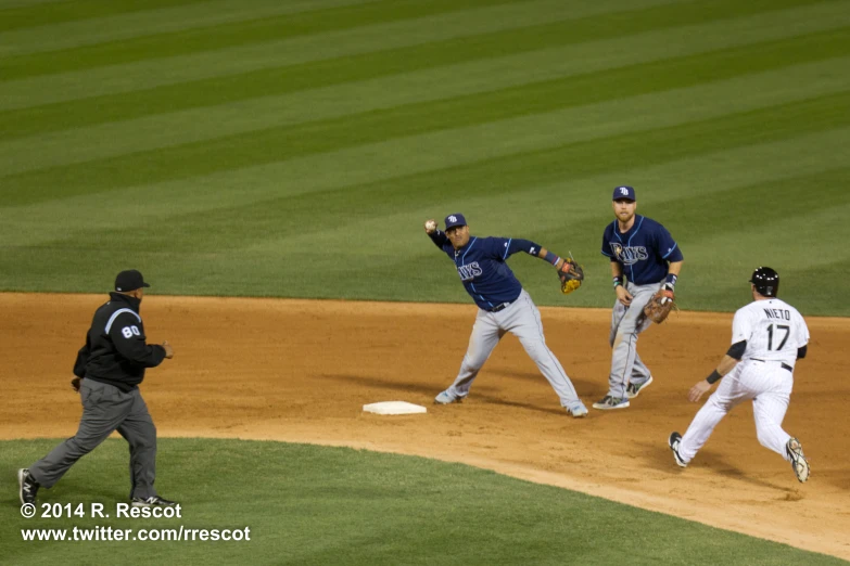 three baseball players running across a base on the field