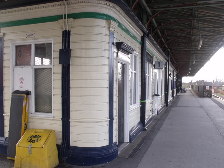 a train station with a white and green train passing by