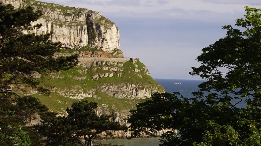 the cliff side next to the ocean with an old castle on it