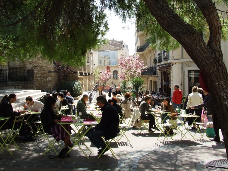a crowd of people sitting at tables in a courtyard