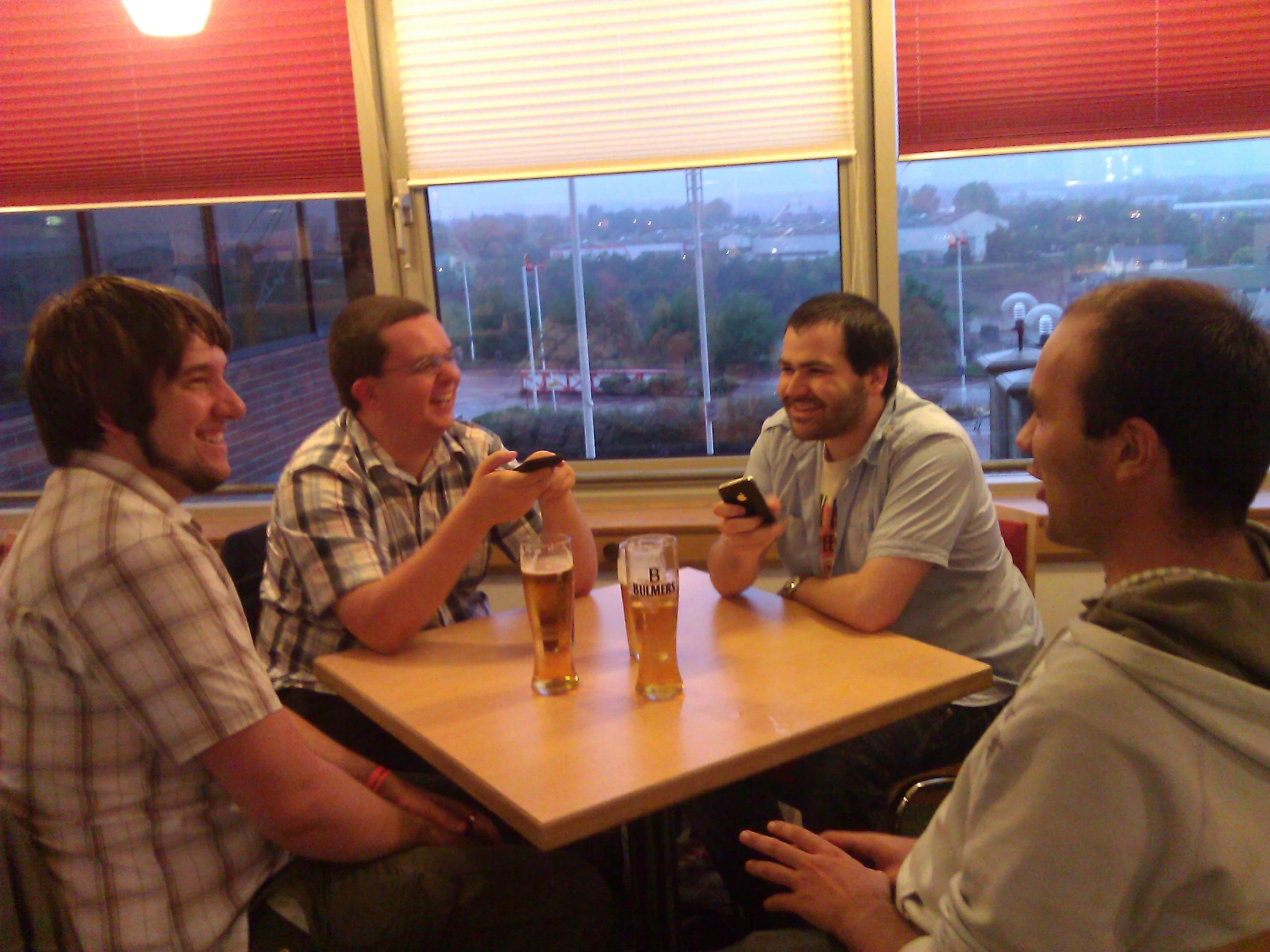 a group of men sitting around a table with beers