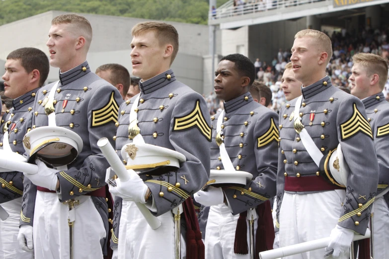 a line of military men standing in front of a crowd