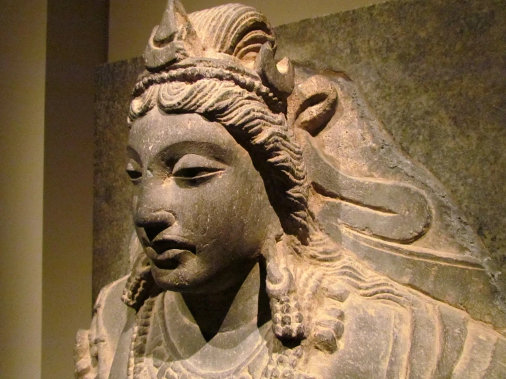 a busturine of the head and shoulders of an indian woman with flowers on her hair and pearls