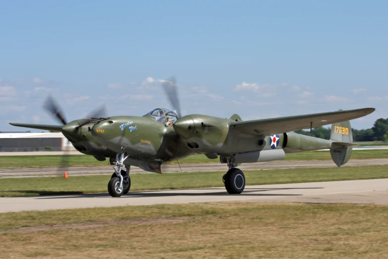 a green fighter airplane with four propeller