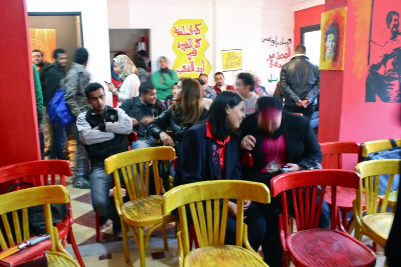 people sitting in a crowded room on bright colored chairs